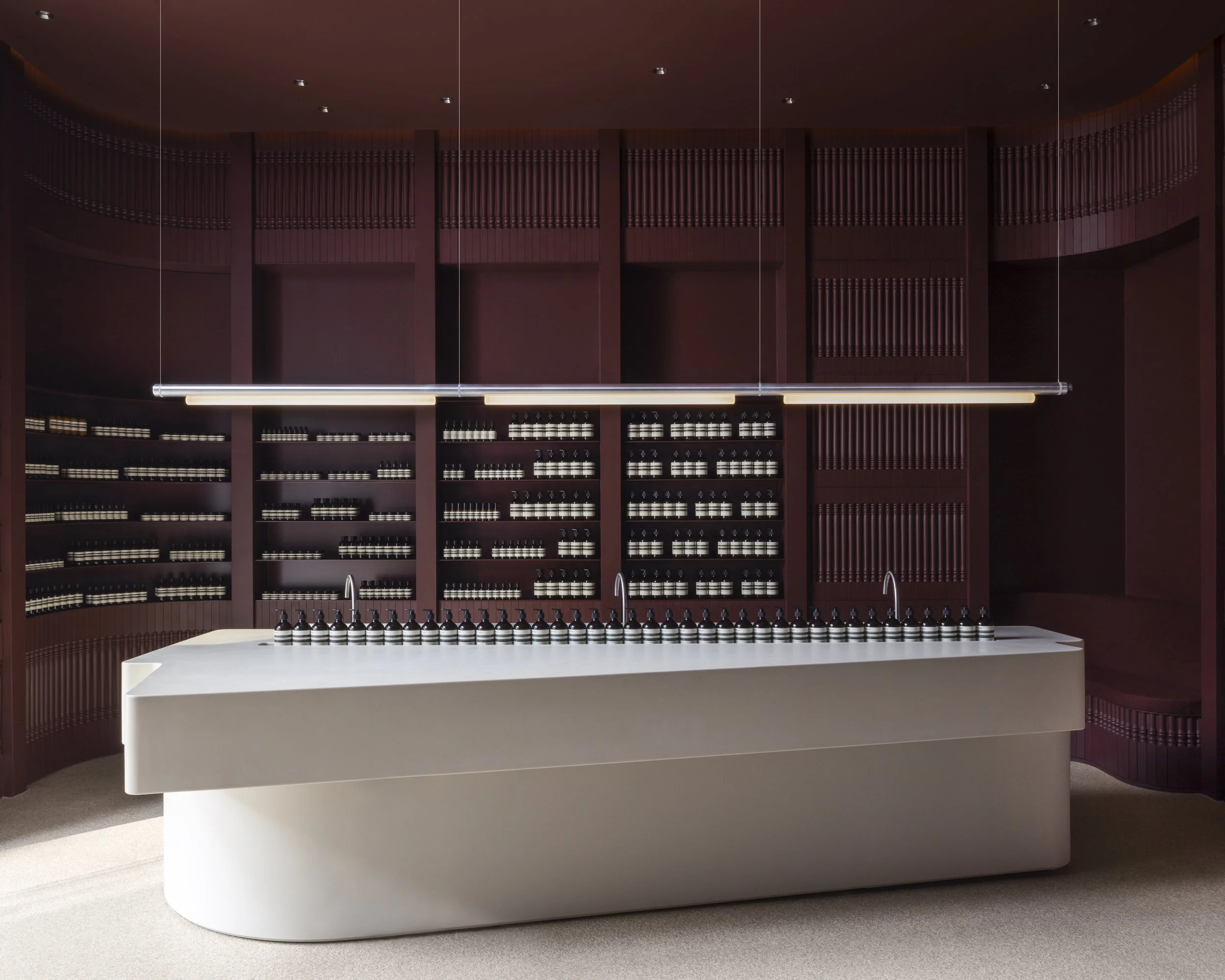 Bassin central clair entouré de rayonnages bordeaux dans la boutique Aesop Yorkville.