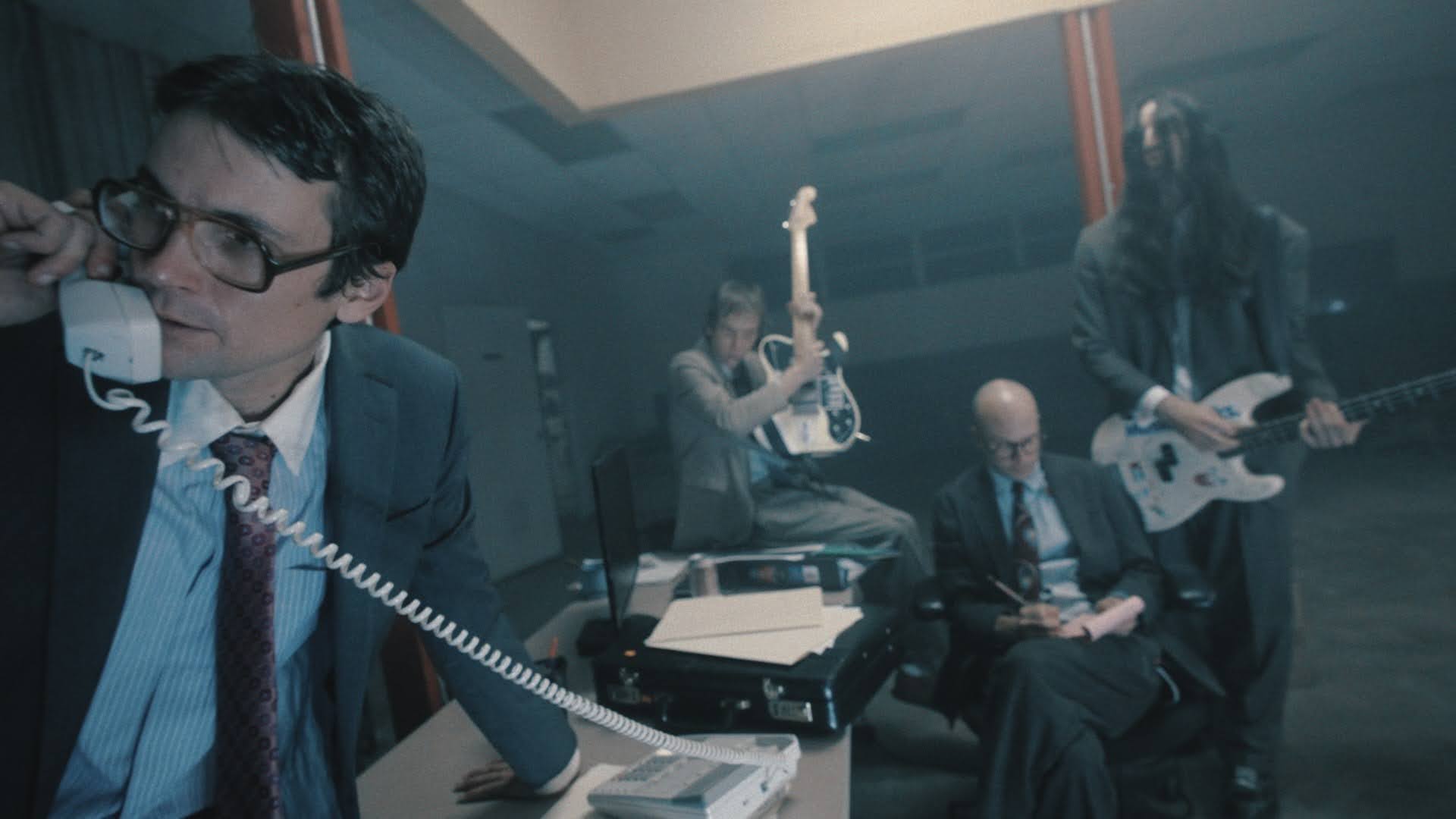 Les membres de DIIV en tenue de bureau froissée dans un local abandonné, image du clip de Dare Me