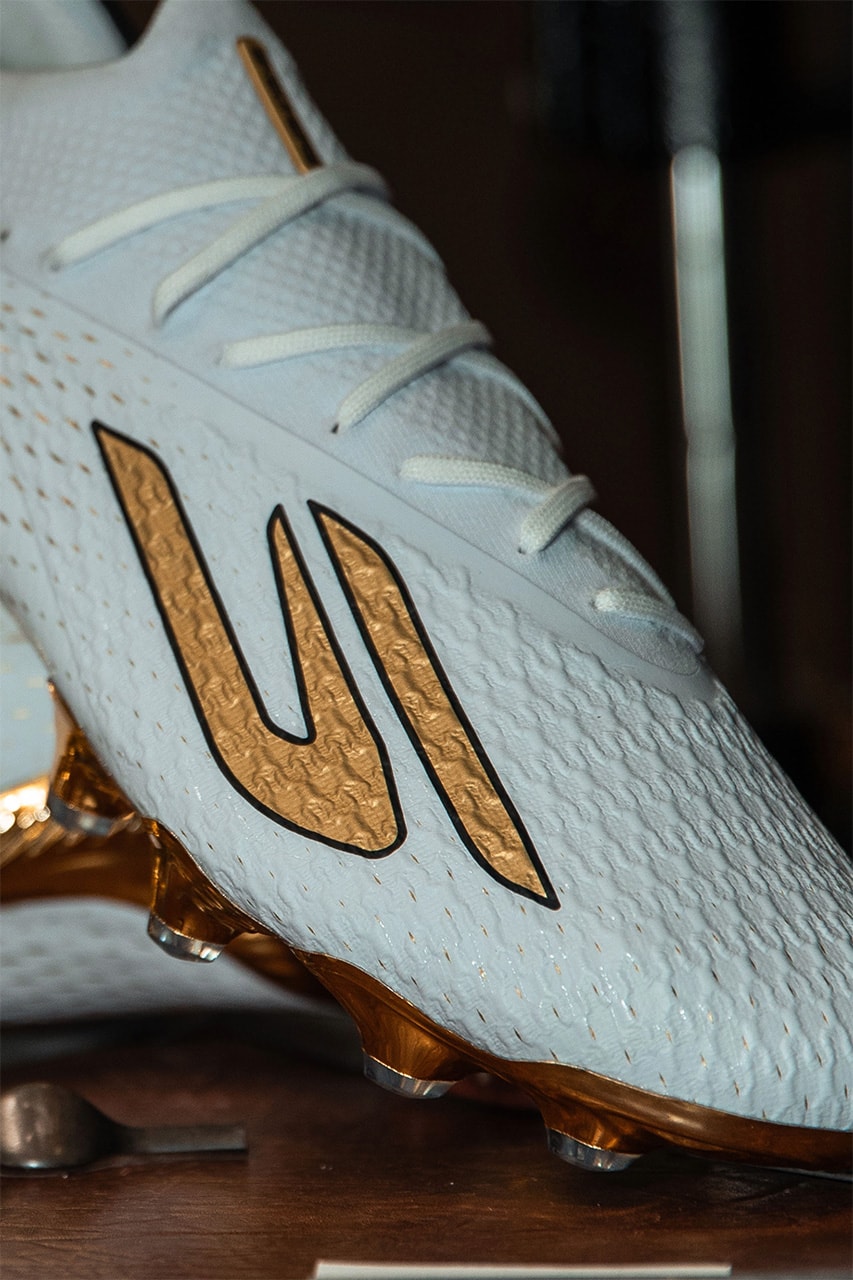 Gros plan sur le logo S doré bordé de noir d'un crampon blanc à semelle dorée.