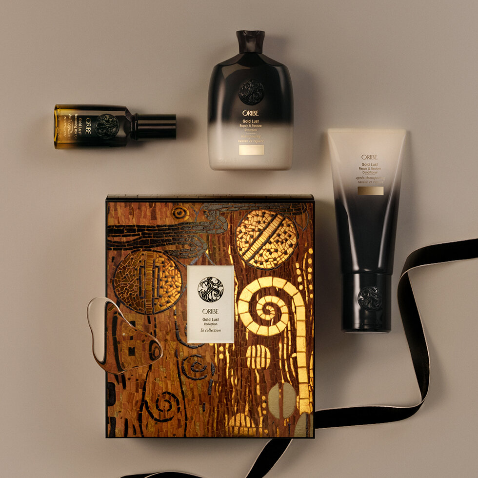 Coffret Gold Lust d'Oribe au couvercle orné d'une mosaïque dorée et cuivrée, entouré d'un shampooing, d'un après-shampooing et d'une huile.