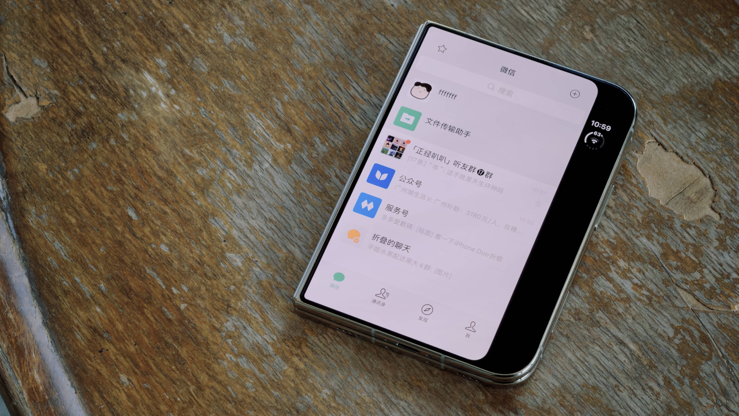 iPhone Duo posé sur une table en bois, WeChat affiché sur l'écran intérieur avec une bande noire à droite